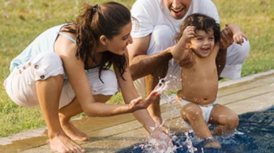 Parents holding child side of pool